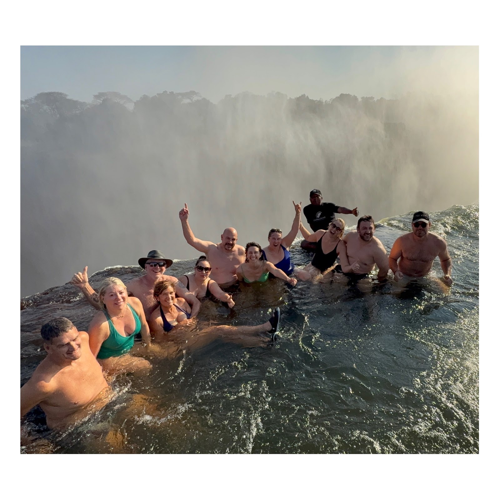 Workshop guests celebrating together in Devil’s Pool above Victoria Falls