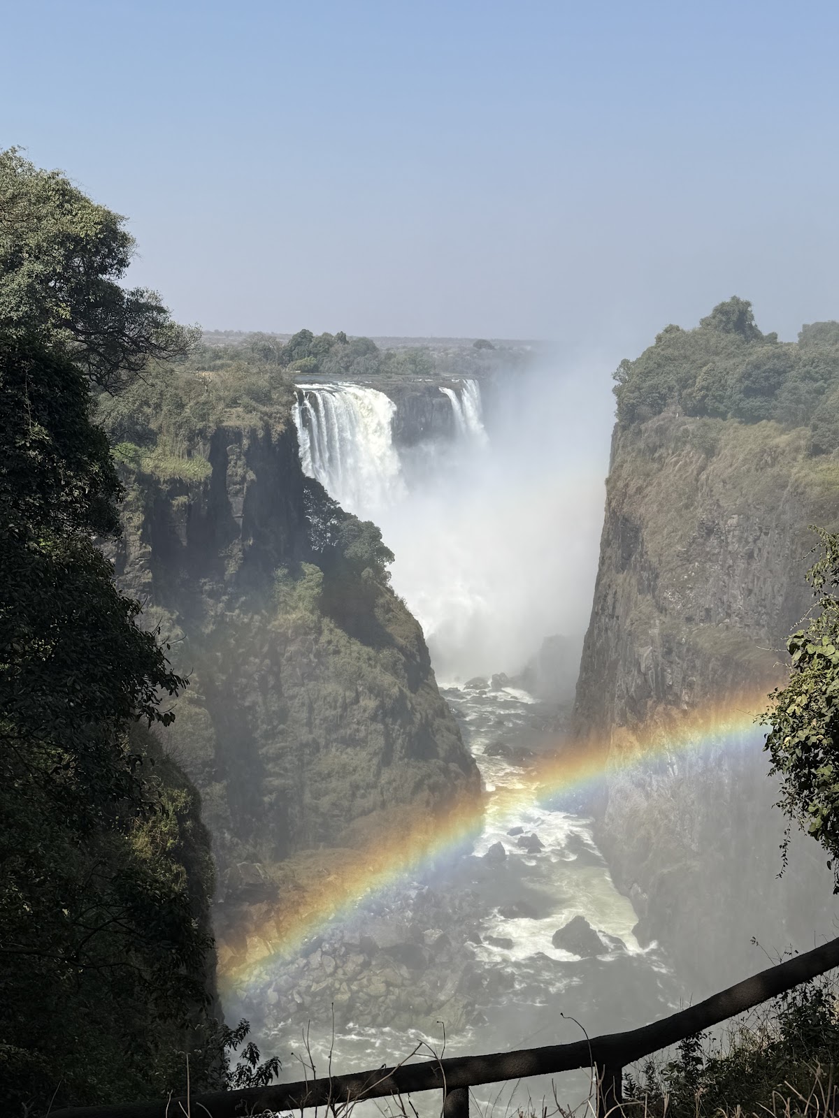 Victoria Falls framed by the gorge with a rainbow rising through the spray