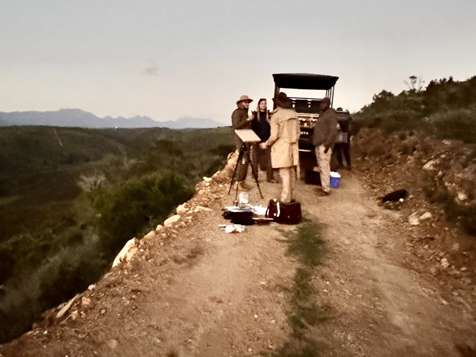 Workshop artists preparing to paint on a hilltop road at sunset